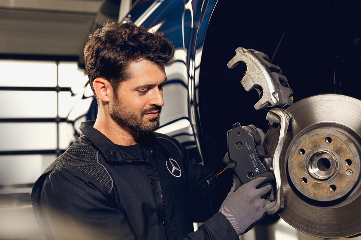 Ein KFZ-Mechatroniker wechselt die Bremsklötze an einem Mercedes-Benz.