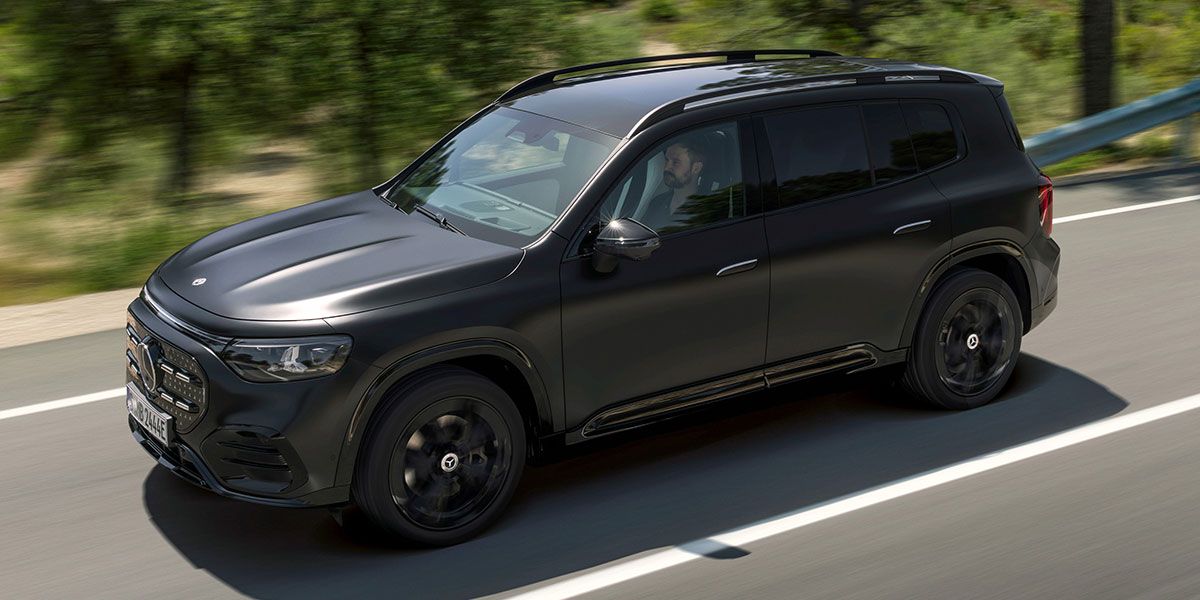Der neue vollelektrische GLB während der Fahrt auf der Straße, Fahrerseite zu sehen, in kosmosschwarz magno