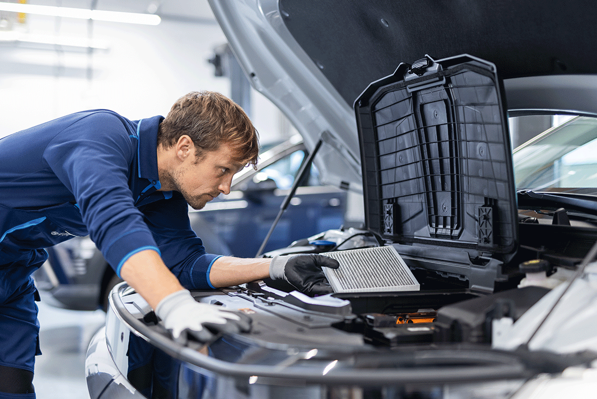 Mann mit braunem Haar und blauer Hyundai Kleidung überprüft die Klimaanlage in einem Hyundai