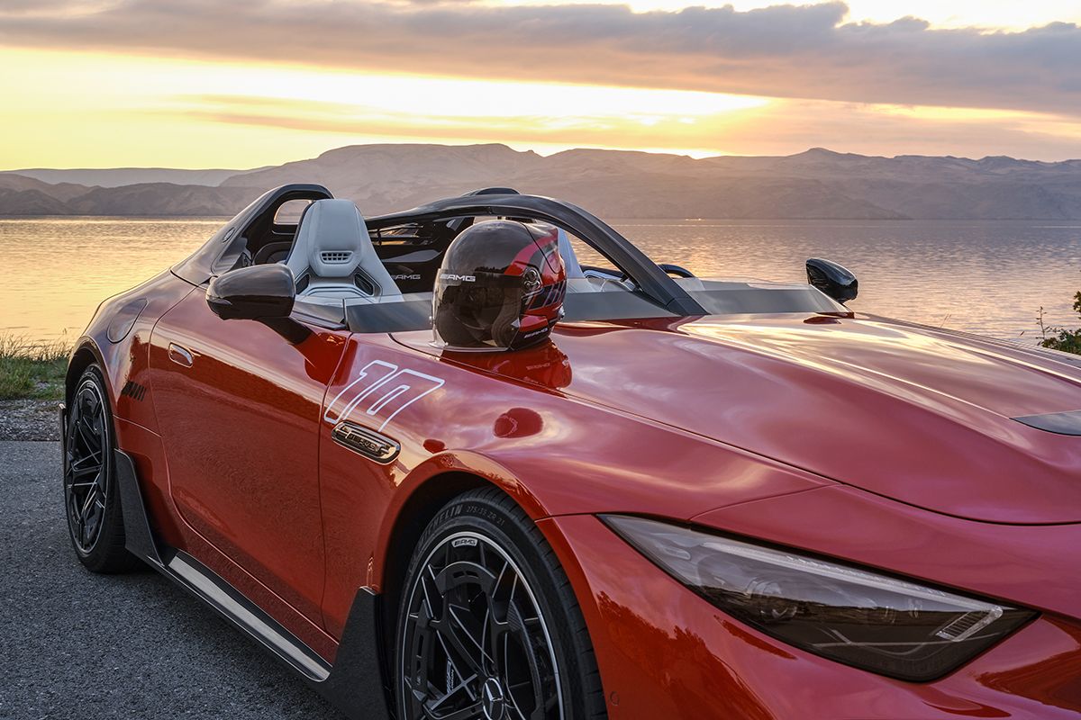 Roter Mercedes-AMG PureSpeed mit passendem Helm am Meer bei Sonnenuntergang.