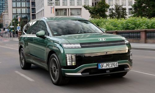 Hyundai IONIQ 9 in IONOSPHERE GREEN fahrend in der Großstadt im Sommer. Frontansicht