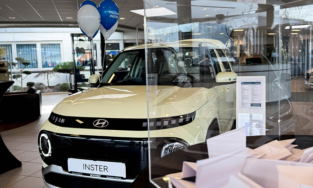 Gewinnspielbox mit Loszetteln im Vordergrund mit Hyundai INSTER im Hintergrund